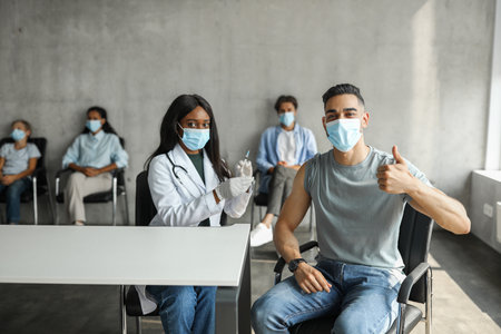 Middle-eastern guy getting vaccinated against coronavirus at clinicの写真素材