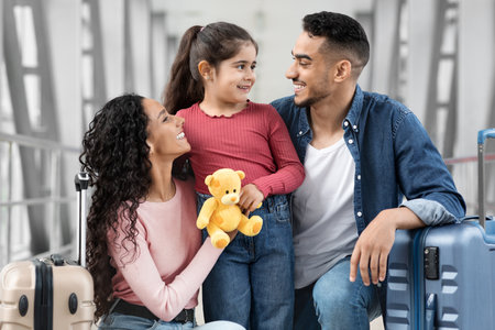 Happy Family at the Airport Preparing for Their Trip While the Daughter Holds a Teddy Bearの写真素材