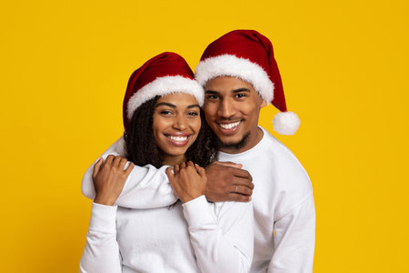 Smiling Couple Celebrating Christmas in Matching Santa Hats Against a Bright Yellow Backdropの写真素材