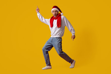 Holiday Dance Celebration With Joyful Man in Festive Attire Against Yellow Backdropの写真素材