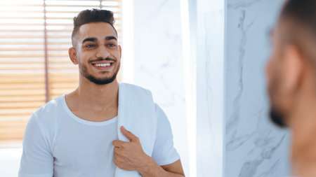Man Smiling in Bathroom While Looking at Mirror After Shower in Bright Lightの写真素材