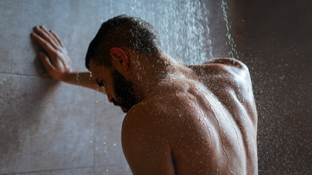 Man Enjoying a Refreshing Shower in a Modern Bathroom With Natural Lightingの写真素材