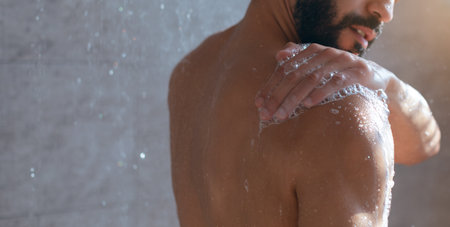Man Enjoying a Relaxing Shower in a Modern Bathroom With Soft Lighting and Water Dropletsの写真素材