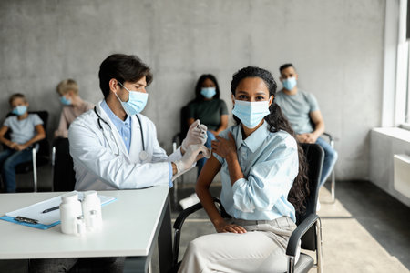 Woman in face mask getting vaccinated at clinicの写真素材