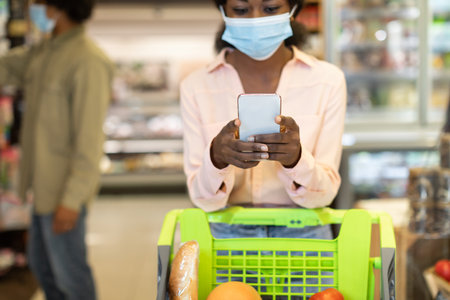 Woman Using Smartphone While Shopping for Groceries in a Supermarket During Daytimeの写真素材
