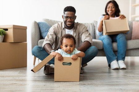 Happy African American Family Enjoys Moving Day in New Apartment Togetherの写真素材