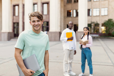 Group of Students Enjoying a Sunny Day on Campus With Laptops and Books in Hand Engaging in Study Activities Togetherの写真素材