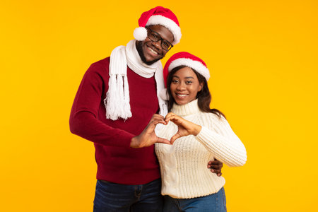 Couple in Santa Hats Make Heart Gesture for Christmas Joyの写真素材