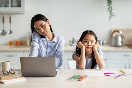 Freelancer Mother Focused on Work While Daughter Seeks Attention at Homeの写真素材