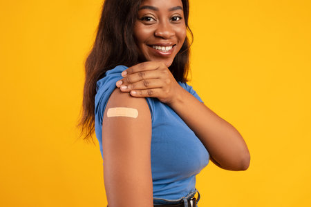 African American Woman Proudly Displaying Her Vaccinated Arm Against a Bright Yellow Background