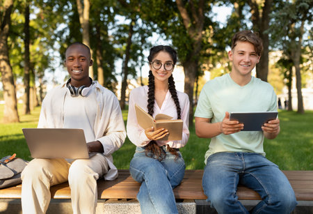 Students Work Together in a Park Using Laptops and Tablets During a Sunny Afternoon
