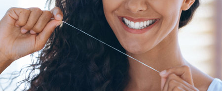 Smiling Woman Demonstrates Proper Dental Flossing Technique in Bright Setting