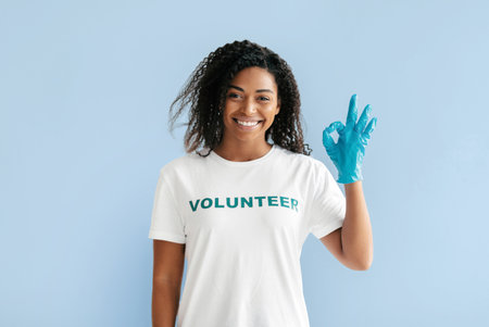 Smiling Volunteer Gives a Positive Sign While Preparing for Community Service Eventの写真素材