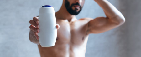 Man Holding Bottle in Bathroom While Showering, Focused on Personal Care and Grooming Routineの写真素材