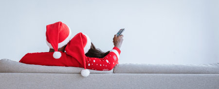 Couple in Christmas Hats Enjoying a Cozy Movie Night at Home Together on the Sofa