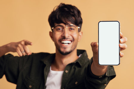 Young Man Happily Showing Smartphone With Blank Screen in Cheerful Atmosphereの写真素材