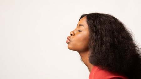 Young Black Woman Pouting Lips in Profile Over White Backgroundの写真素材