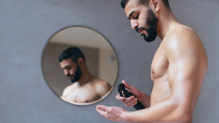 Man Applying Grooming Product in Front of Mirror in Modern Bathroomの写真素材