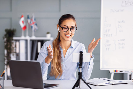 Woman Teaching Online Class With a Laptop and Whiteboard in a Well-Lit Office Space
