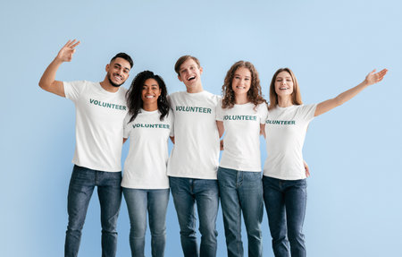 Group of Smiley Volunteers Pose Together in Light Blue Studio With Matching Shirtsの写真素材
