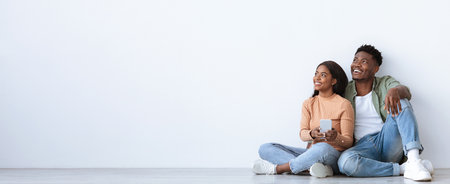 Young Couple Enjoying Time Together While Sitting on the Floor and Looking at a Phoneの写真素材