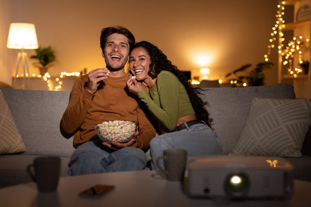 Couple Enjoys a Comedy Film Together With Popcorn Using a Home Cinema Projector Indoorsの写真素材