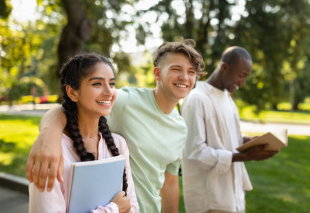 Group of Friends Enjoying a Sunny Day in the Park, Engaging in Conversation and Reading Togetherの写真素材