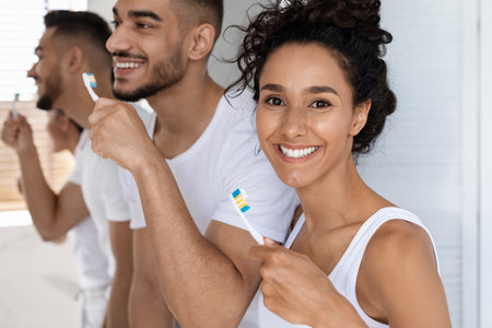 Group of Friends Practicing Good Oral Hygiene While Brushing Their Teeth in a Bright Bathroomの写真素材