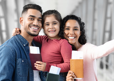 Family Celebrates Travel Plans While Holding Passports and Smiling at Camera in a Bright Locationの写真素材
