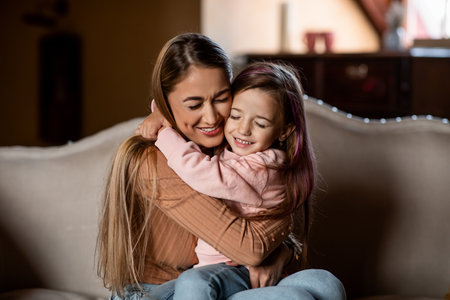 Mother and Daughter Share a Warm Embrace on a Cozy Sofa in a Living Roomの写真素材