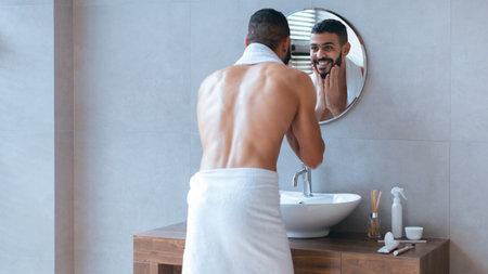 Man Grooming in Bathroom Mirror While Wearing a Towel During Morning Routineの写真素材