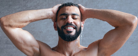 Man Enjoying a Refreshing Shower While Smiling Under Warm Water in a Modern Bathroomの写真素材