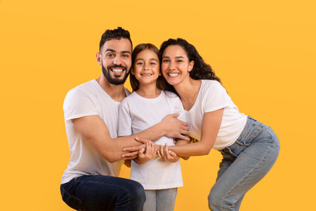 Family Embraces Each Other Against a Bright Yellow Background During a Cheerful Moment Togetherの写真素材