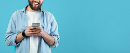 Smiling Man Using Smartphone Against Blue Backgroundの写真素材