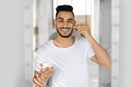Smiling Young Man Pointing at His Face in a Bright Indoor Setting During the Dayの写真素材