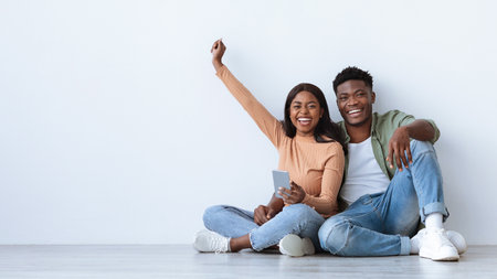 Couple Enjoying a Joyful Moment While Sitting on the Floor in a Spacious Roomの写真素材