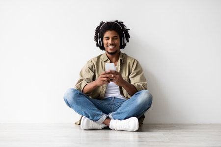 Relaxing Young Man Smiles While Enjoying Music With Smartphone and Headphonesの写真素材