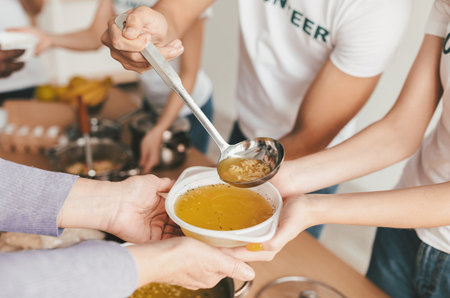 Volunteers Serve Soup at a Community Kitchen During a Warm Gathering Eventの写真素材