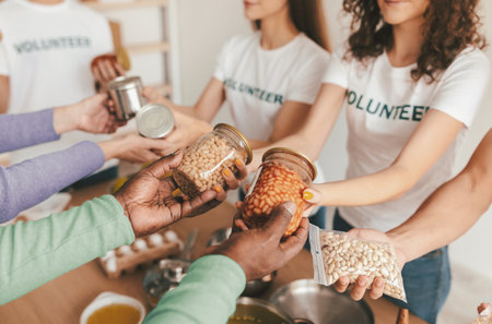 Group of Volunteers Sharing Jars of Food at a Community Kitchen During a Service Eventの写真素材