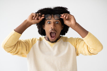Surprised Black Man Takes off Glasses and Reacts With Joy on a White Backgroundの写真素材
