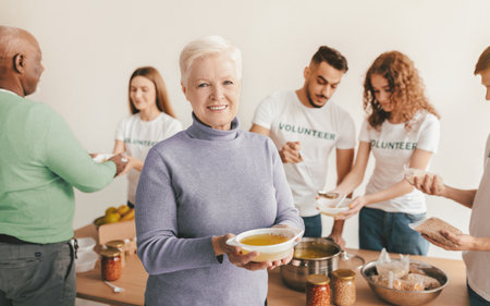 Volunteers Serving Food and Smiling at a Community Event in a Cozy Indoor Settingの写真素材