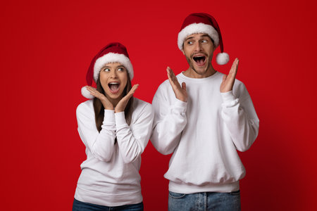 Holiday Celebration With Cheerful Friends in Festive Santa Hats Against a Bright Red Backdropの写真素材