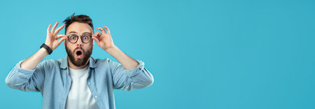 Man Wearing Glasses Expresses Surprise in Front of a Blue Backgroundの写真素材