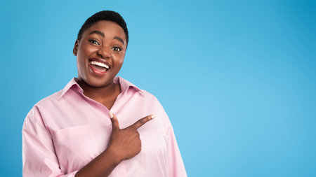 Smiling Woman in Pink Shirt Pointing With Joy Against a Bright Blue Background