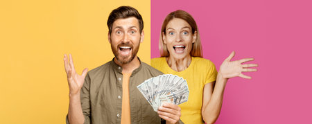Excited Couple Celebrating With Cash in a Colorful Studio Settingの写真素材