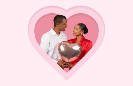 Romantic Couple Sharing a Sweet Moment With Heart-Shaped Balloon in a Soft Pink Backdropの写真素材