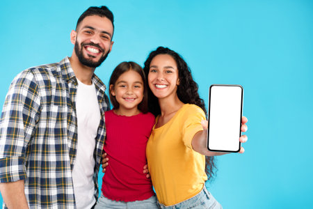 Happy Family Posing Together With a Smartphone Against a Bright Blue Backgroundの写真素材