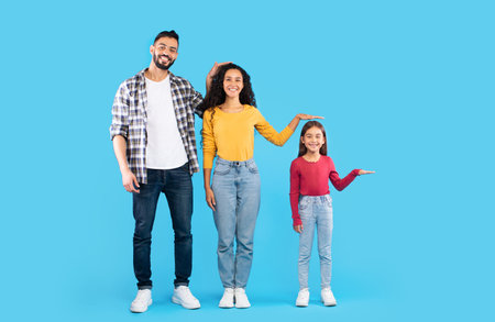 Family Standing Together Against a Blue Background Showcasing Height Differences in a Playful Manner