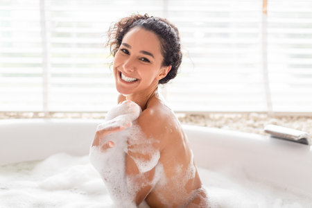 Smiling Woman Relaxing in a Bubble Bath at Home During a Calm Afternoonの写真素材
