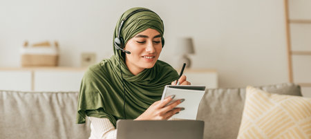 Student Engaged in Online Learning With Headset and Notepad in Cozy Home Settingの写真素材